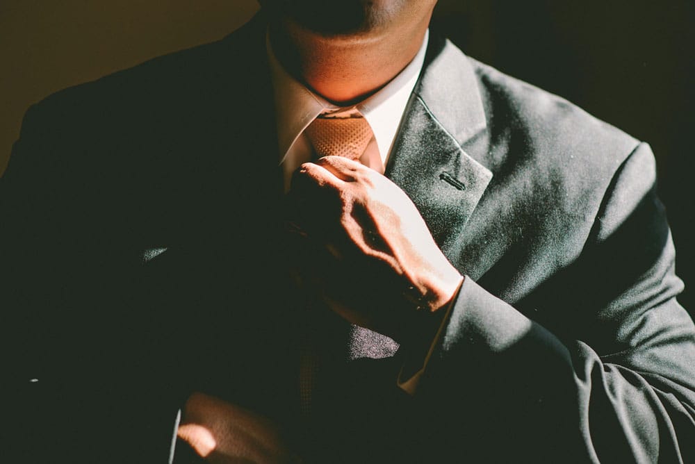 man in black suit adjusting tie